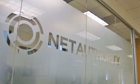 Office glass wall with a frosted band carrying a large cut-out company logo, an example of branded privacy frost on interior glass